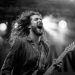 Expressive guitarist passionately performing live on stage in black and white.